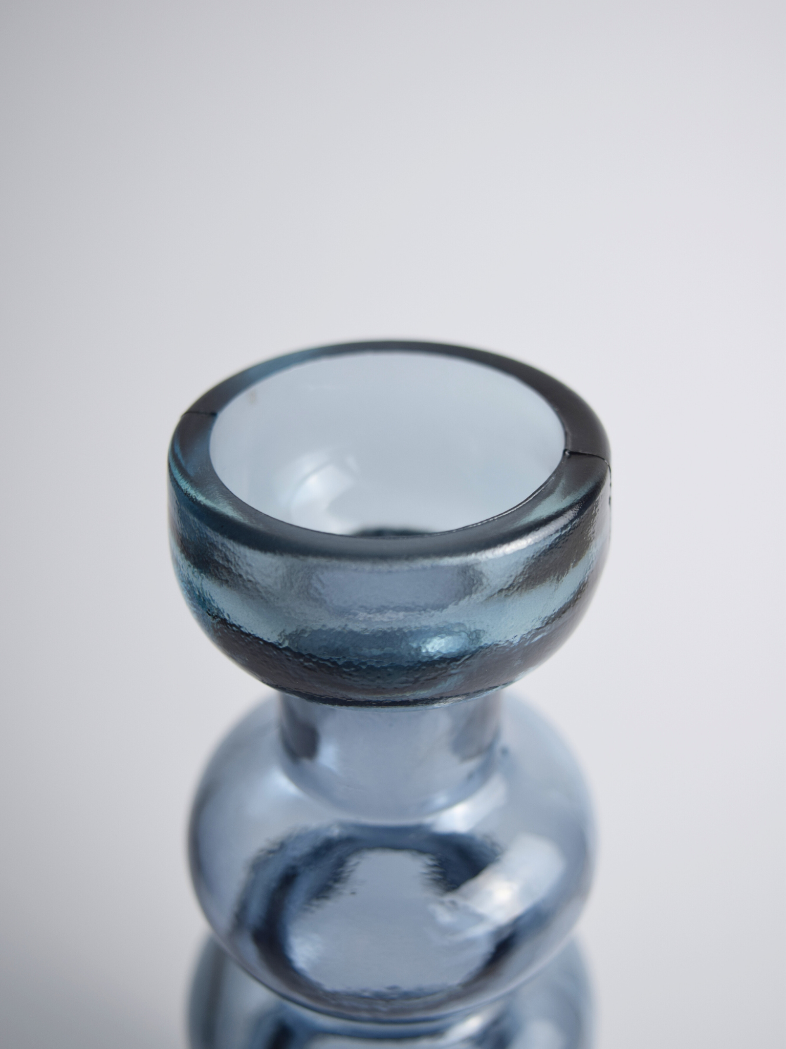 Nahaufnahme eines blauen, gewölbten Kerzenhalter vor einem weissen Hintergrund