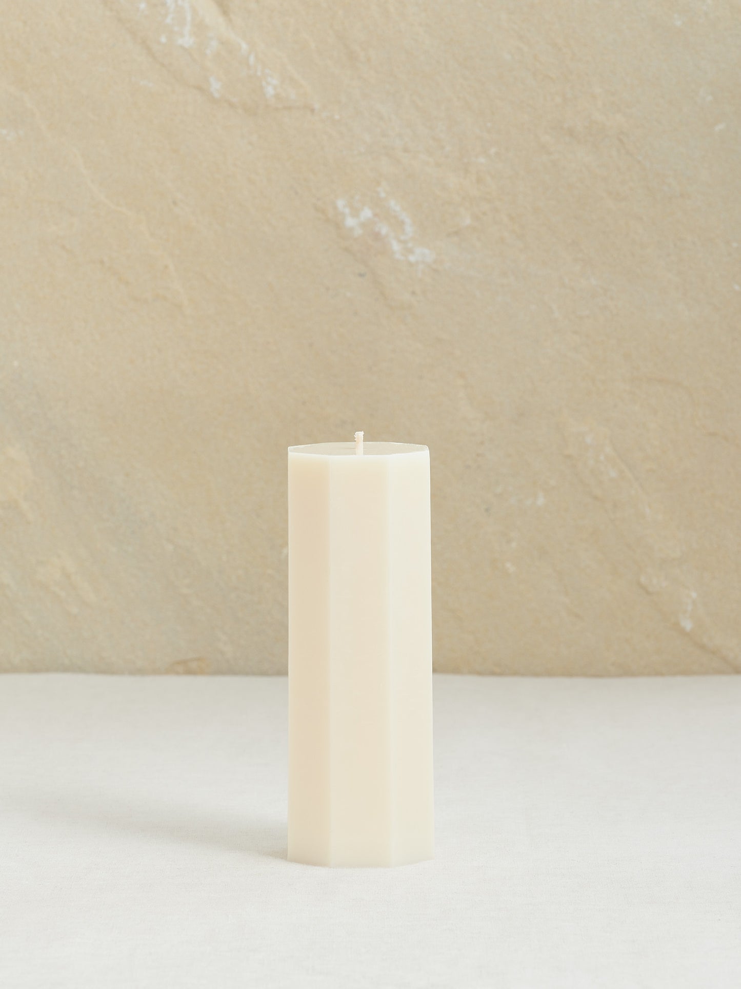 Minimalistische, achteckige Dekokerze auf neutralem Hintergrund, naturweiss