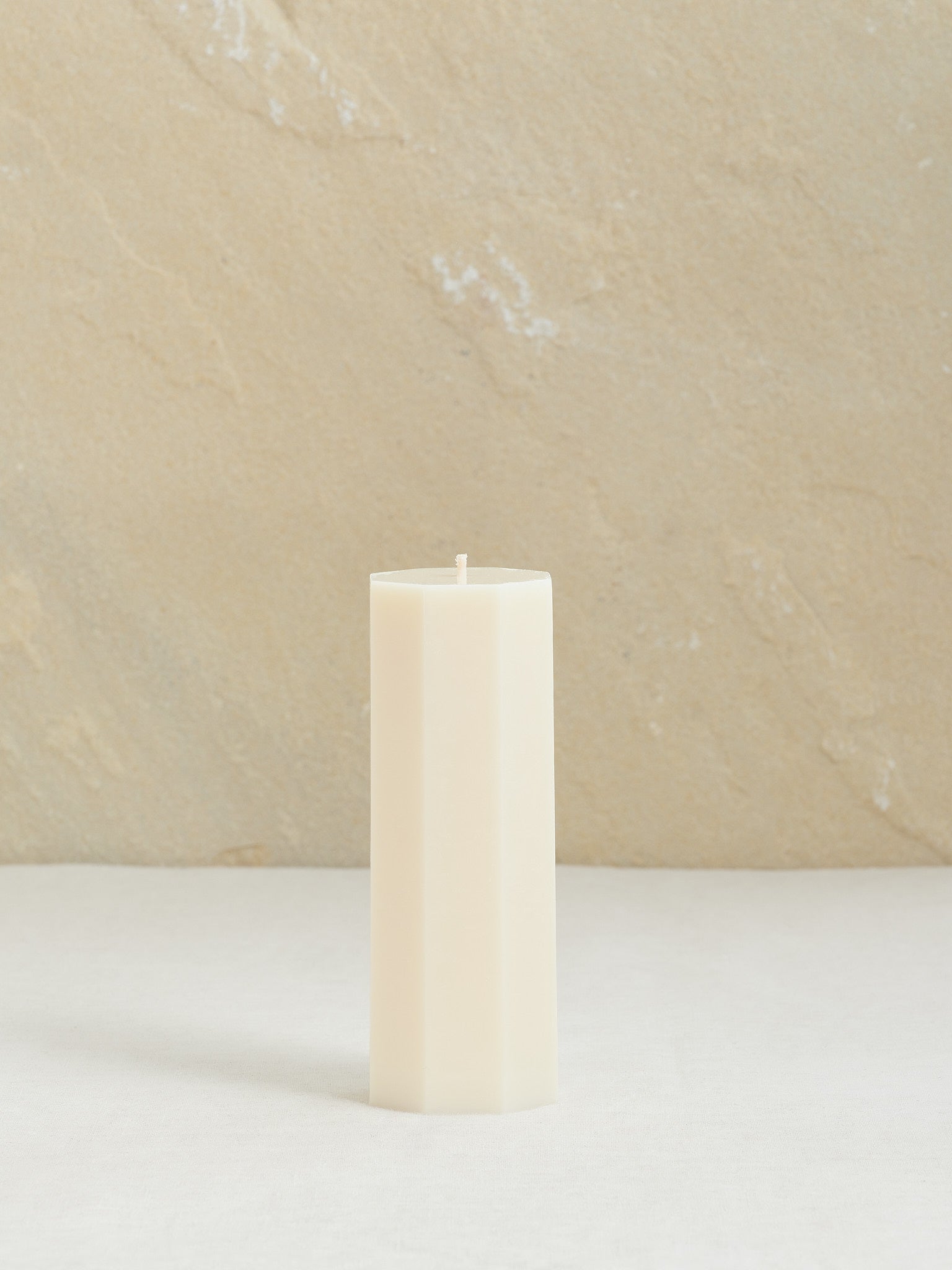 Minimalistische, achteckige Dekokerze auf neutralem Hintergrund, naturweiss