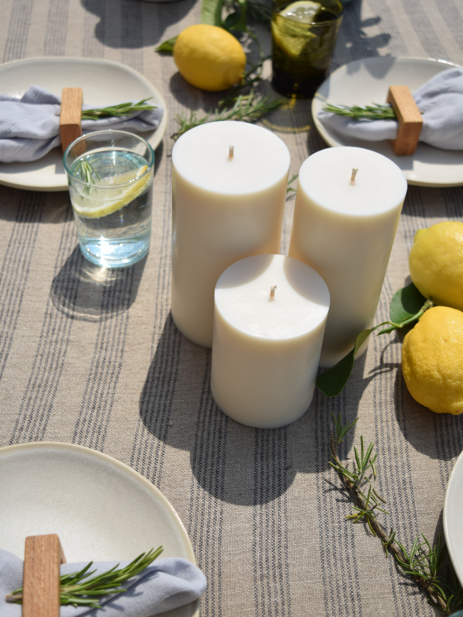 Drei Zylinderkerzen auf einem sommerlich gedeckten Tisch